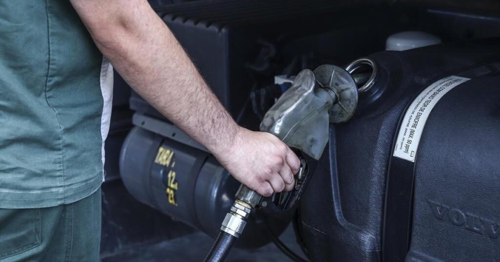 Frentista abastecendo um caminhão com óleo diesel.